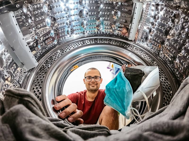 man putting face masks in washing machine cm